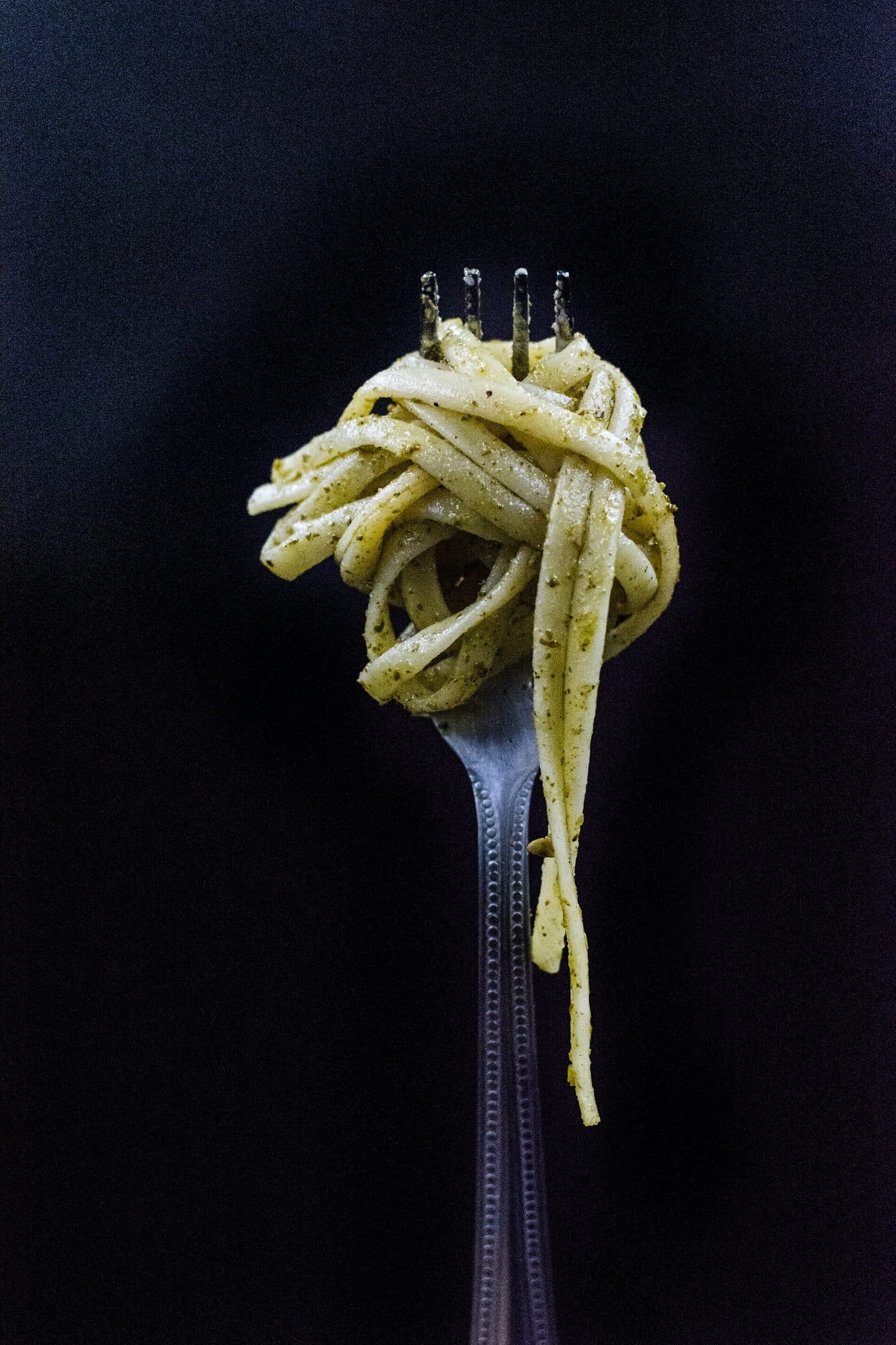Dark slate surface with pasta and a fork: texture background